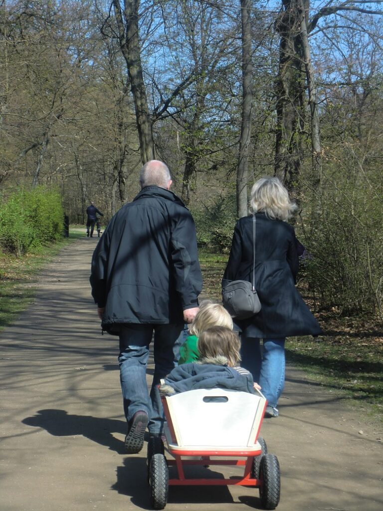 Pareja caminando de espaldas arrastrando un carrito con una niña